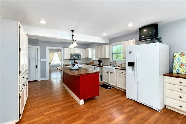 314 N Lake St, Pleasant Hill, MO 64080 - kitchen with stainless steel microwave, wood finished floors, white cabinets, and white fridge with ice dispenser