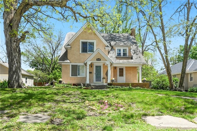314 N Lake St, Pleasant Hill, MO 64080 - view of front of house featuring covered porch, stucco siding, a chimney, and a front lawn