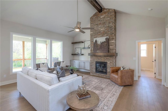 living room with wood-type flooring, a ceiling fan, baseboards, and beam ceiling
