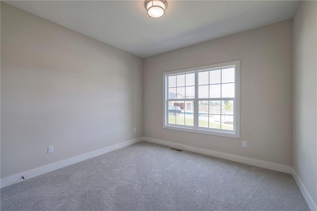 unfurnished room with baseboards, visible vents, and light carpet