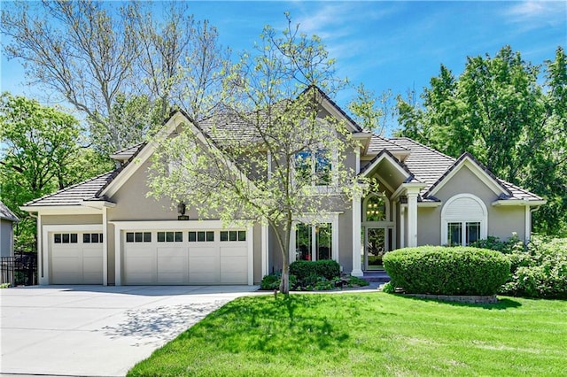 view of front of home with stucco siding, driveway, an attached garage, and a front yard