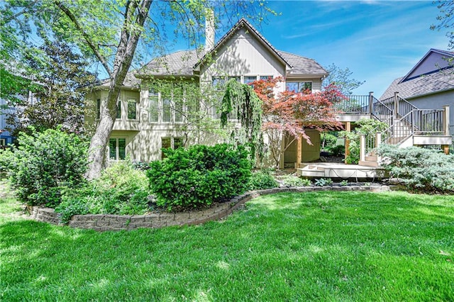 rear view of property featuring stairs, a deck, a lawn, and a chimney
