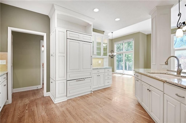 kitchen with a sink, light wood-style floors, white cabinetry, glass insert cabinets, and recessed lighting