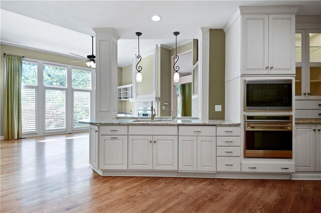 kitchen featuring ceiling fan, light wood-style floors, white cabinetry, a sink, and light stone counters