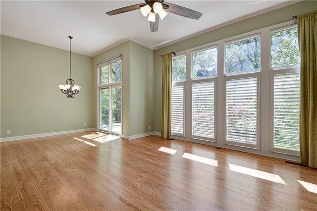 spare room with ornamental molding, healthy amount of natural light, a ceiling fan, light wood-type flooring, and a chandelier
