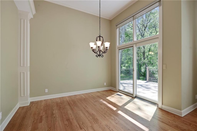 unfurnished dining area with light wood-style flooring, crown molding, a chandelier, and baseboards