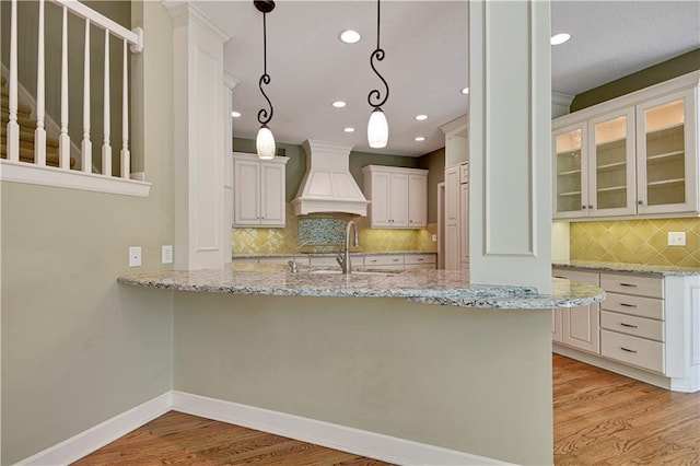 kitchen featuring premium range hood, a sink, backsplash, recessed lighting, and light wood finished floors