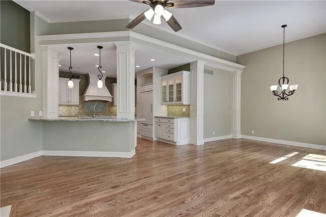 kitchen featuring a ceiling fan, wood finished floors, backsplash, and crown molding