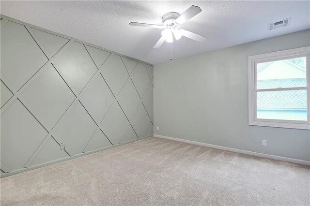 empty room featuring a ceiling fan, carpet floors, baseboards, and a textured ceiling