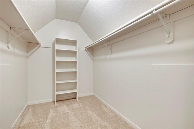 spacious closet with vaulted ceiling and light colored carpet
