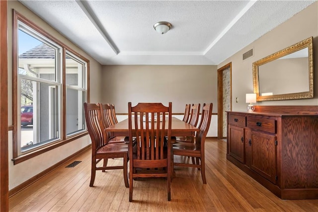 6732 Clairborne Rd, Shawnee, KS 66217 - dining space featuring light wood-style floors, baseboards, a raised ceiling, and a textured ceiling