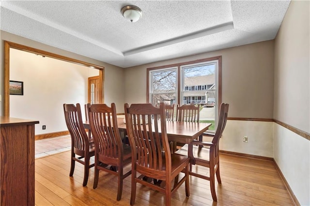 6732 Clairborne Rd, Shawnee, KS 66217 - dining room featuring a textured ceiling, a tray ceiling, light wood-style floors, and baseboards