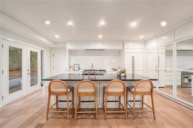 9440 Manor Rd, Leawood, KS 66206 - kitchen featuring oven, dark countertops, light wood-style floors, french doors, and white cabinetry