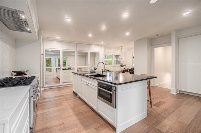 9440 Manor Rd, Leawood, KS 66206 - kitchen with appliances with stainless steel finishes, a sink, light wood-type flooring, white cabinets, and an island with sink