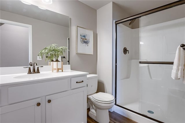 bathroom with toilet, a shower stall, wood finished floors, and vanity