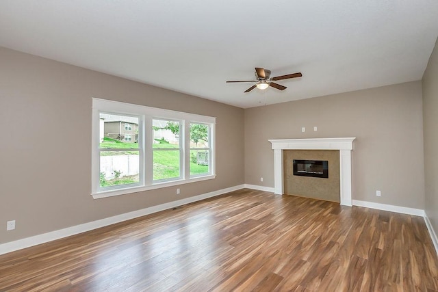 unfurnished living room with a glass covered fireplace, baseboards, a ceiling fan, and wood finished floors
