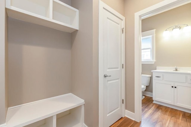 mudroom with baseboards, a sink, and light wood-style floors