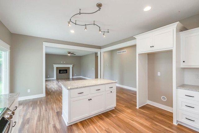 8411 NW 90th St, Kansas City, MO 64153 - kitchen featuring visible vents, baseboards, white cabinets, a glass covered fireplace, and light wood-style floors