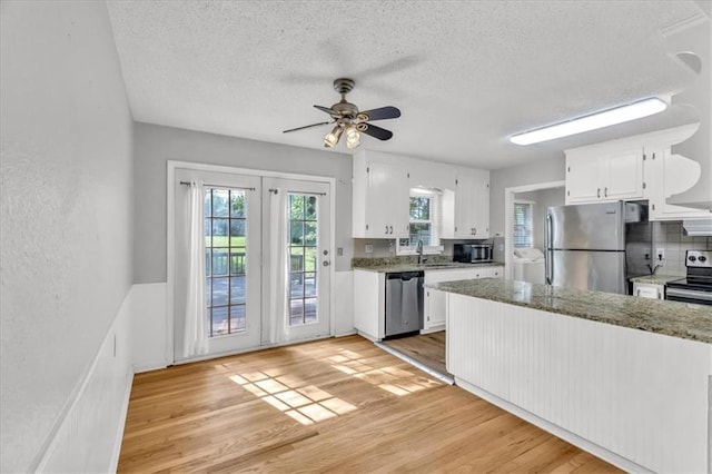 7934 Maple St, Prairie Village, KS 66208 - kitchen with stainless steel appliances, white cabinets, light wood-style floors, a textured ceiling, and a ceiling fan
