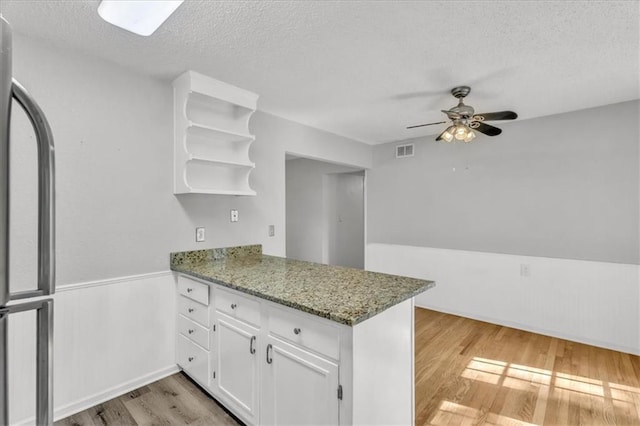 7934 Maple St, Prairie Village, KS 66208 - kitchen with a peninsula, light wood-type flooring, a textured ceiling, white cabinetry, and open shelves