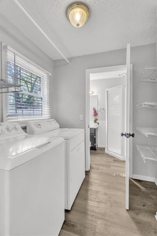 7934 Maple St, Prairie Village, KS 66208 - clothes washing area featuring washer and clothes dryer, a textured ceiling, and light wood finished floors