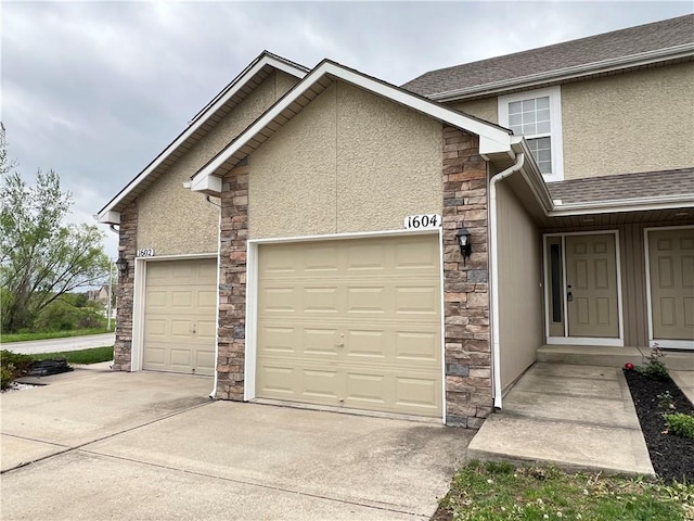 view of front of house with a garage, stone siding, roof with shingles, stucco siding, and driveway