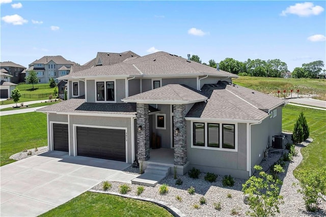 view of front of property with a front yard, a garage, central AC, concrete driveway, and stucco siding