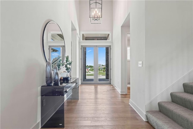 entrance foyer featuring baseboards, an inviting chandelier, stairway, and hardwood / wood-style floors