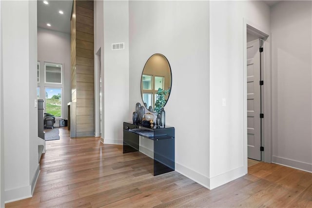 corridor featuring visible vents, baseboards, and wood finished floors