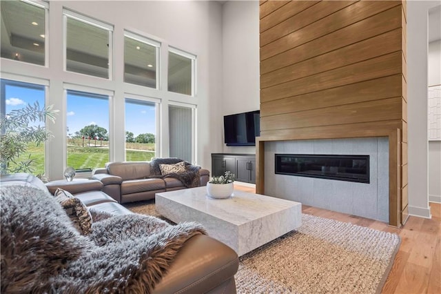 living area featuring a towering ceiling, light wood-style flooring, and a fireplace