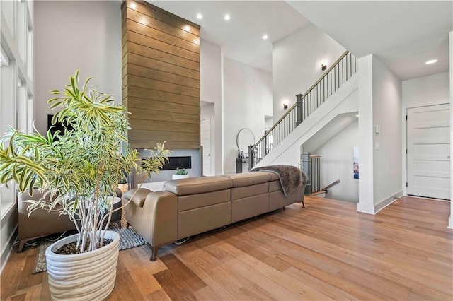 living area featuring a fireplace, stairs, wood finished floors, and a towering ceiling