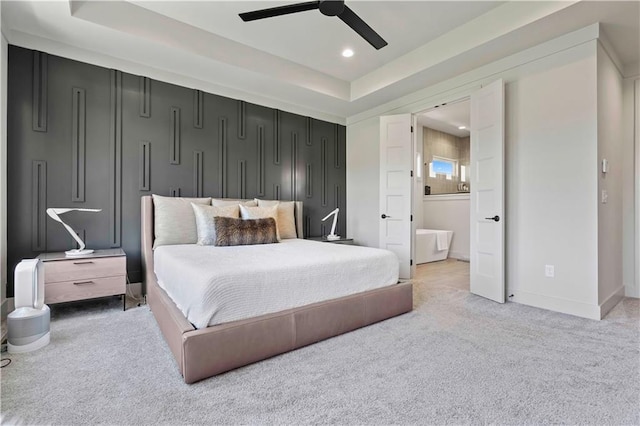bedroom featuring light carpet, ensuite bath, recessed lighting, a ceiling fan, and a tray ceiling