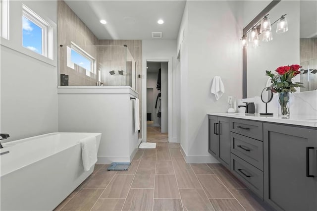 full bathroom featuring visible vents, vanity, recessed lighting, a walk in shower, and a freestanding bath