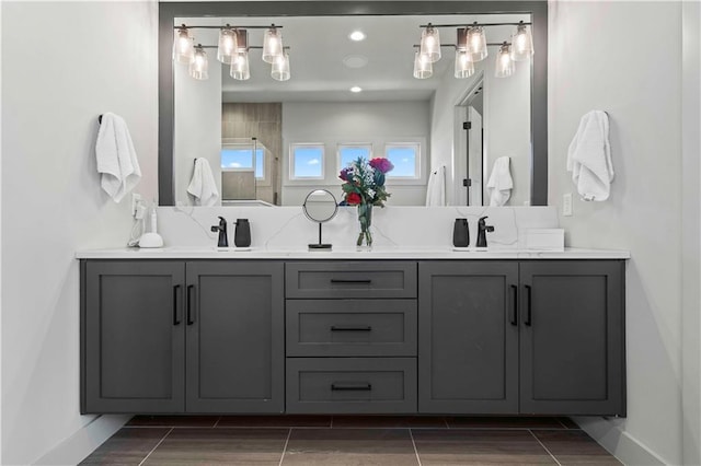 full bathroom featuring baseboards, double vanity, wood finish floors, and a sink