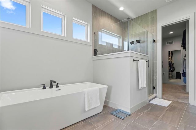 full bath with a walk in closet, recessed lighting, a freestanding tub, a shower stall, and visible vents