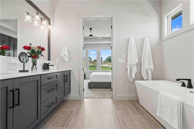 bathroom with plenty of natural light, double vanity, a ceiling fan, and a soaking tub