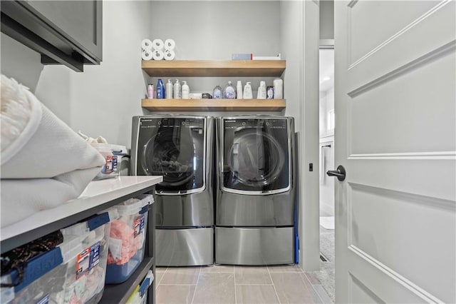 washroom with cabinet space, light tile patterned floors, and washing machine and clothes dryer