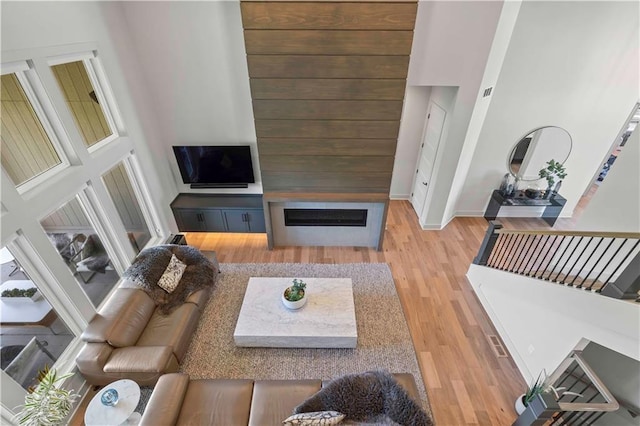 living room with baseboards, a high ceiling, wood finished floors, and a fireplace