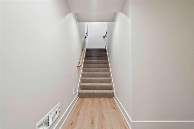 stairs with baseboards, visible vents, and wood finished floors