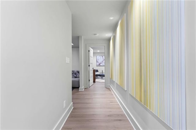 hall featuring baseboards, recessed lighting, and light wood-style flooring