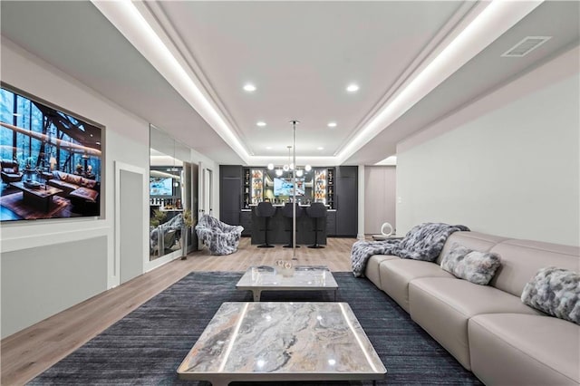 living room featuring visible vents, an inviting chandelier, wood finished floors, recessed lighting, and a raised ceiling