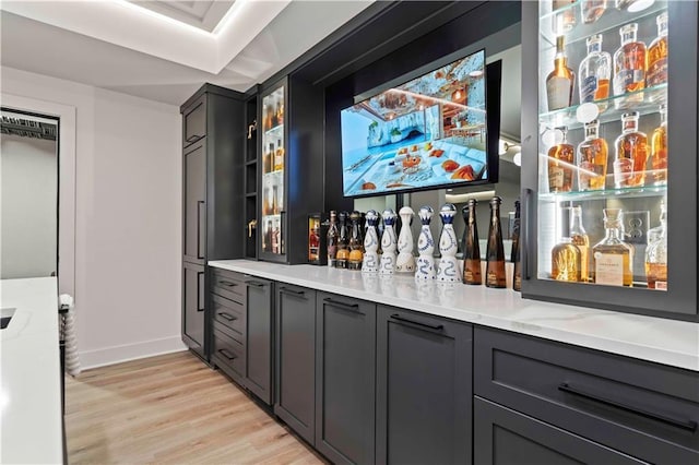 bar with light wood-style floors, a dry bar, and baseboards