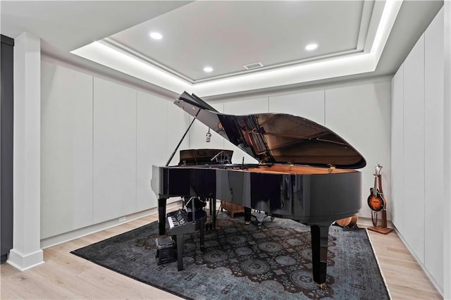 living area featuring recessed lighting, a raised ceiling, light wood-type flooring, and visible vents