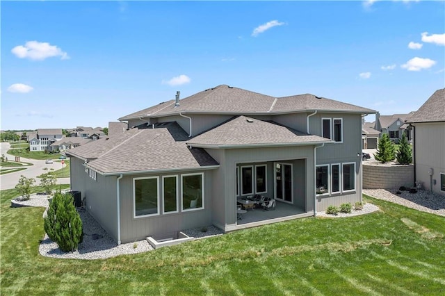 rear view of house featuring roof with shingles, central AC unit, a patio area, a yard, and a residential view