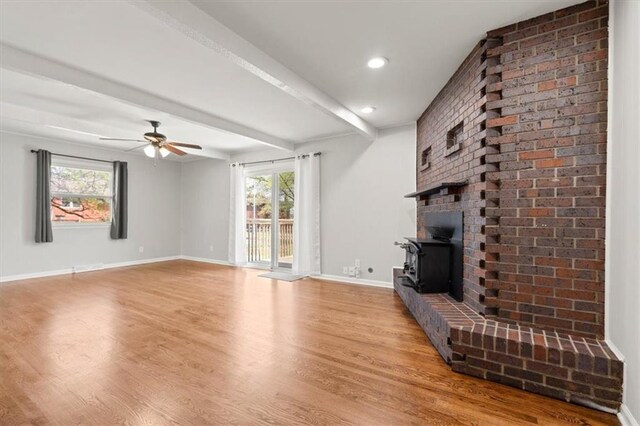 10401 Cypress Dr, Kansas City, MO 64137 - unfurnished living room with baseboards, ceiling fan, wood finished floors, and a wood stove