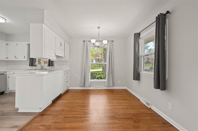 10401 Cypress Dr, Kansas City, MO 64137 - kitchen featuring plenty of natural light, a chandelier, and white cabinets