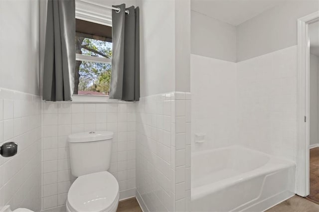 10401 Cypress Dr, Kansas City, MO 64137 - full bathroom featuring a shower, toilet, tile walls, a tub, and a wainscoted wall