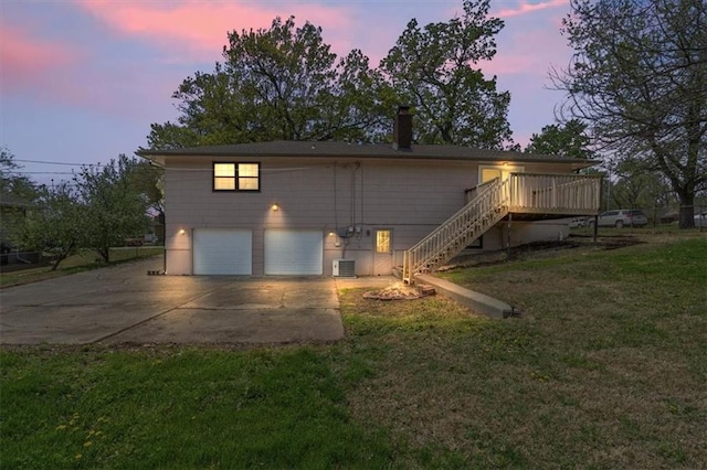 10401 Cypress Dr, Kansas City, MO 64137 - exterior space with a front yard, central AC unit, concrete driveway, an attached garage, and stairs