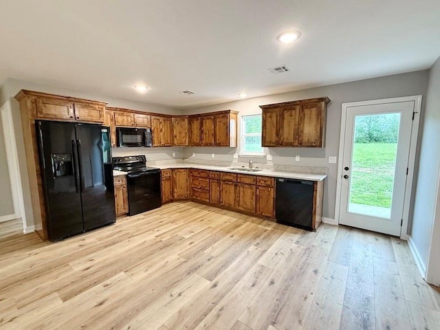 kitchen featuring light wood-style floors, light countertops, brown cabinets, and black appliances