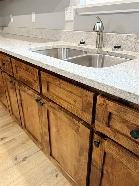 kitchen featuring brown cabinetry, a sink, and light wood-style flooring
